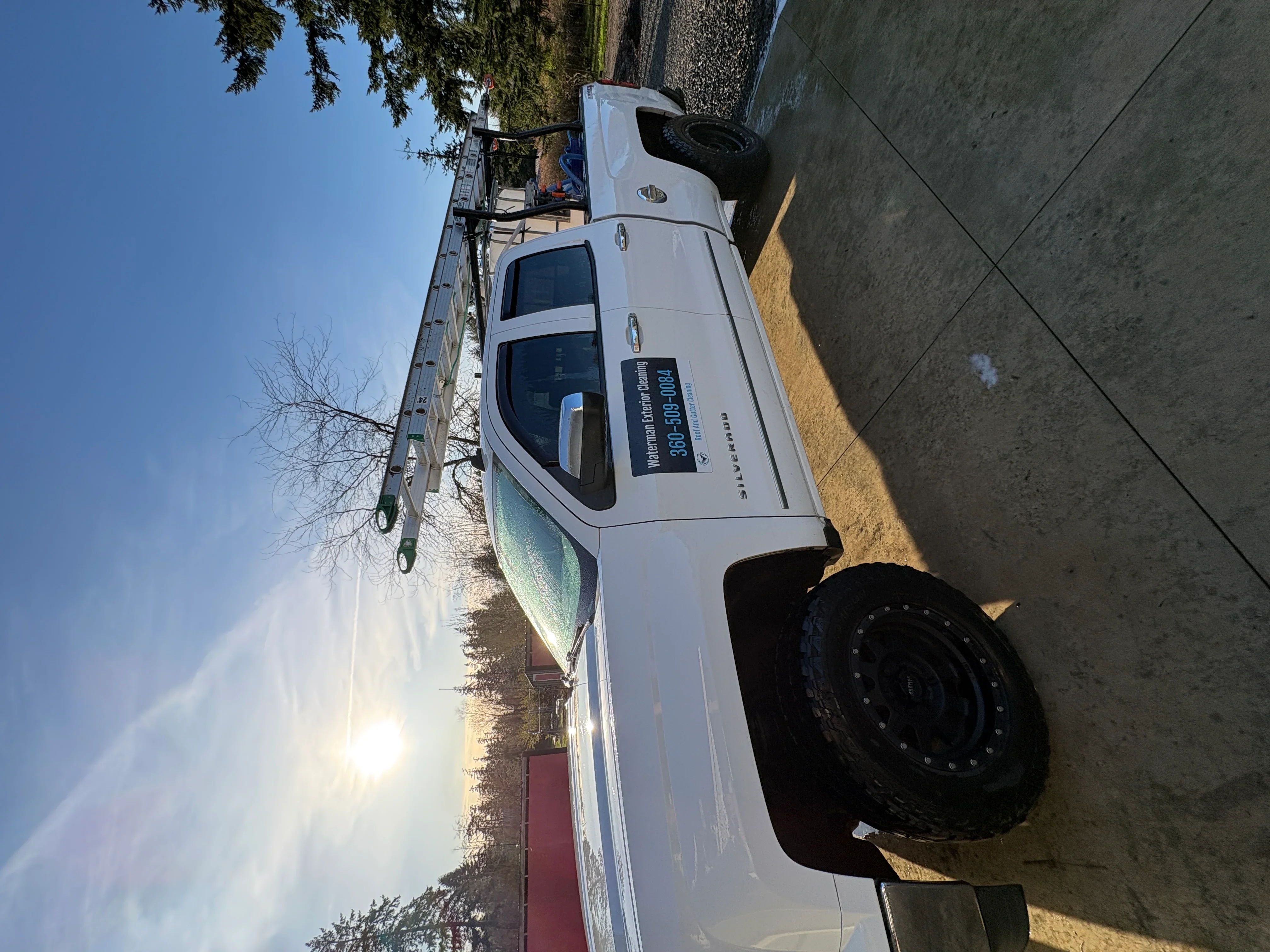 Pressure washing commercial building exterior with truck-mounted equipment and elevated platform access