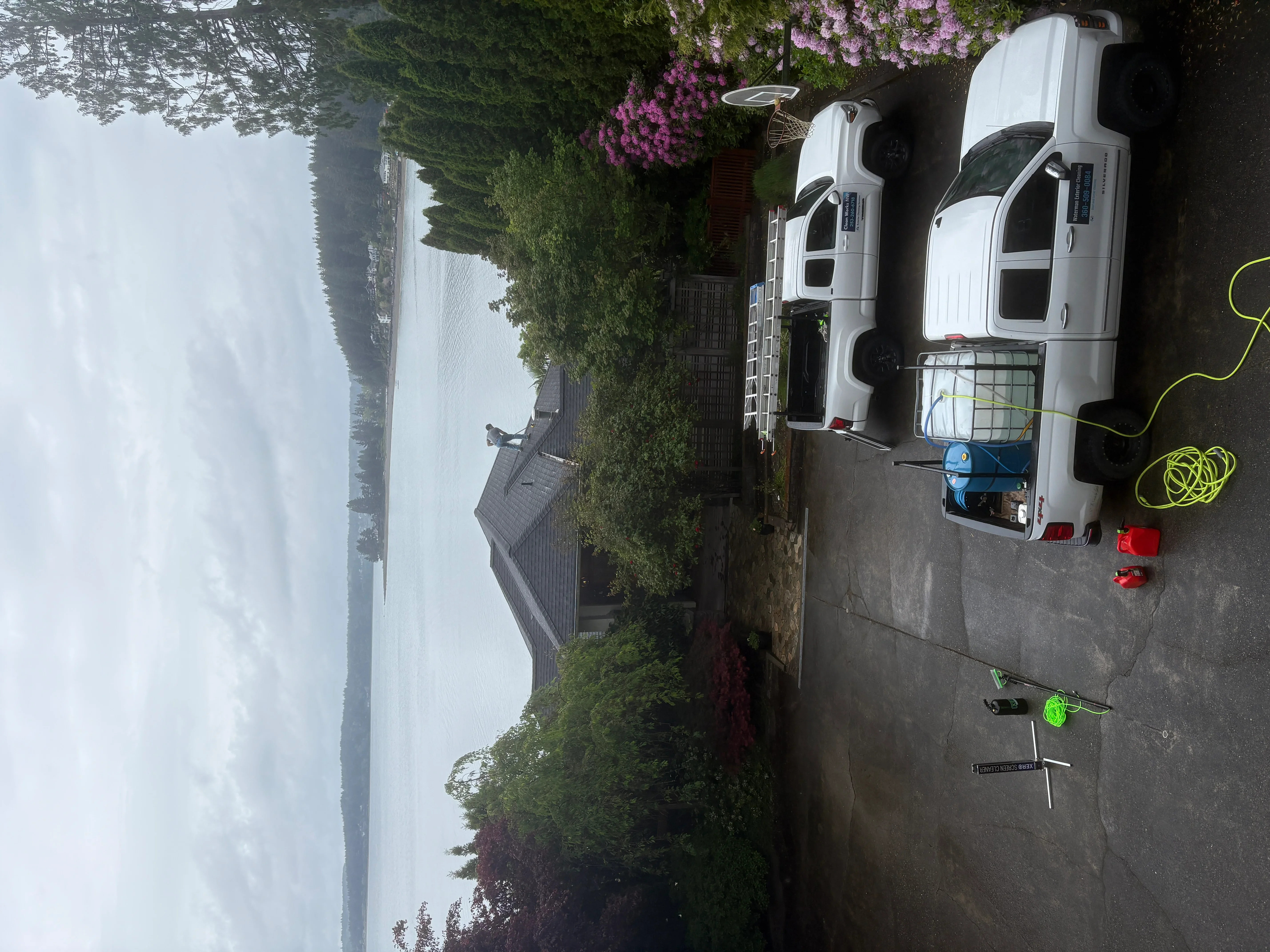 Pressure-washed concrete driveway with service vehicles and equipment staged on residential property