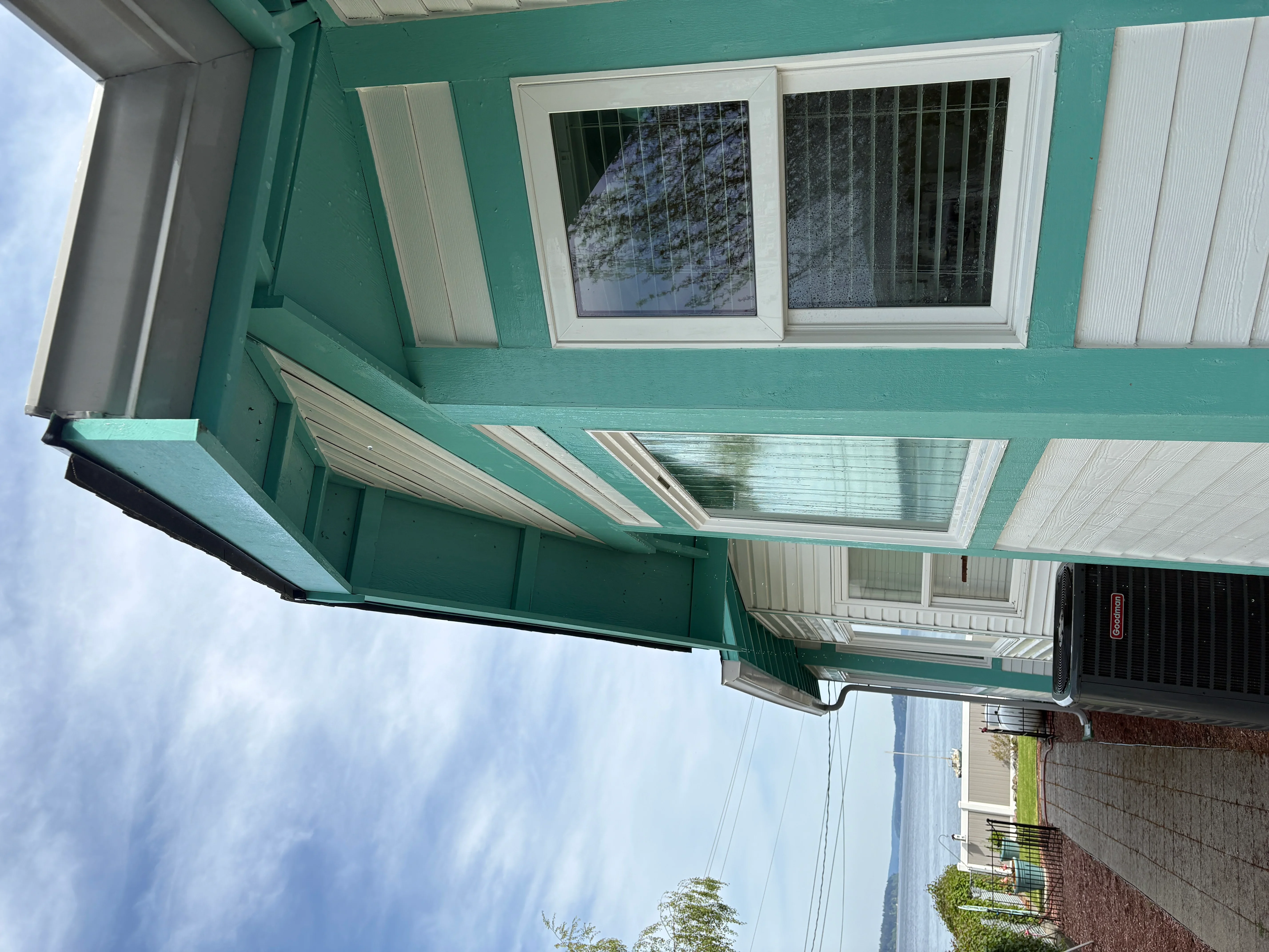 Clean white-framed windows and gutters on turquoise residential exterior